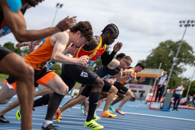 Relay team exchanging baton under stadium lights